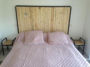 ein Bett mit zwei rosa Kissen und einem Kopfteil aus Holz in der Unterkunft Maison Traditionnelle Rénovée, Proche Plage, Barbâtre - Terrasse, Wifi, Confort Modern - FR-1-426-371 in Barbâtre