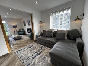 uma sala de estar com um sofá cinzento num quarto com uma janela em Stylish Modern Home with Parking Enclosed Garden em Holyhead