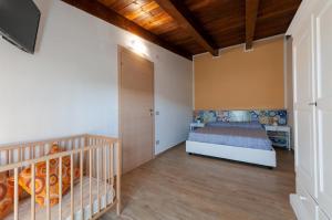 a bedroom with a crib in a room with wooden ceilings at Holiday Mulas in Marina di Casalvelino