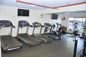 a gym with several tread machines and a flat screen tv at The Moon Apartments in Mutomo