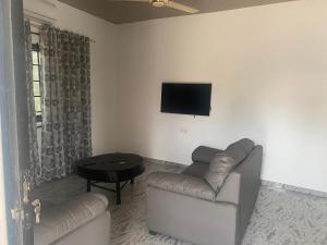 a living room with a couch and a tv on the wall at Arm Beach Lodge in Accra