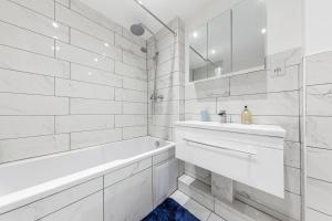 La salle de bains blanche est pourvue d'une baignoire et d'un lavabo. dans l'établissement Modern Flat near Hyde Park, à Londres