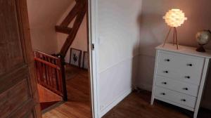 a room with a staircase and a dresser with a lamp on it at Chambre calme et accueillante, parking gratuit, navette gare ou aéroport in Saint-Germain-la-Poterie