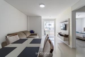 a white living room with a couch and a television at Apto c/ varanda loc. privilegiada em BC BFH0101 in Balneário Camboriú