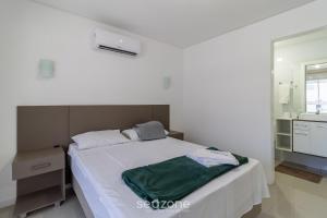 a white bedroom with a bed and a mirror at Apto c/ varanda loc. privilegiada em BC BFH0101 in Balneário Camboriú