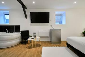 ein Schlafzimmer mit einer Badewanne, einem Bett und einem TV in der Unterkunft NG SuiteHome - Lille l Tourcoing l Haute - Duplex 4 pers - Balnéo - Netflix - Wifi in Tourcoing