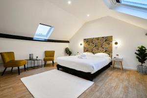 um quarto com uma cama grande e 2 cadeiras em NG SuiteHome - Lille l Tourcoing l Haute - Duplex 4 pers - Balnéo - Netflix - Wifi em Tourcoing