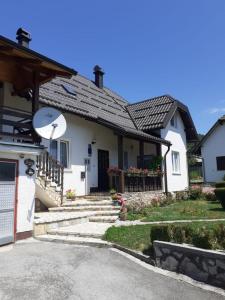 Casa blanca con porche y escaleras delante en Guesthouse Milka en Poljanak