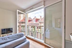 een woonkamer met een bank en een groot raam bij Budget studio with parking - The river seine in Saint-Denis