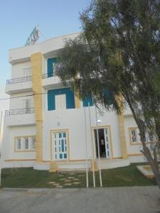 a large white building with blue windows at hotel amilcar tataouine in Tataouine
