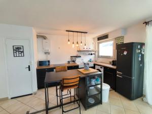 a kitchen with a black refrigerator and a table at Idéal en amoureux, vue mer et jardin ! Appartement lumineux à Tharon-Plage in Saint-Michel-Chef-Chef