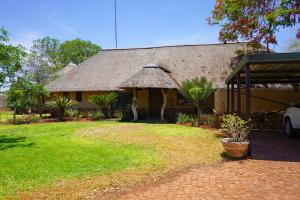 a building with a thatched roof and a grass yard at Lucca House in Musina