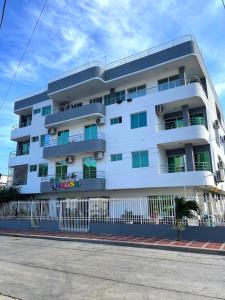 un edificio de apartamentos blanco al lado de una calle en Apartahotel Tukasa Rodadero, en Santa Marta