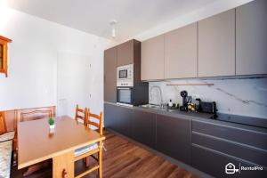 cocina con armarios blancos y mesa de madera en [Elegant Apartment]-con Free Wi-Fi & A/C, en San Remo