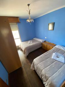 1 dormitorio con 2 camas y pared azul en Balcones de Madrid, en Parada del Sil