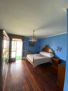 a bedroom with a bed with blue walls and a chandelier at Balcones de Madrid in Parada del Sil