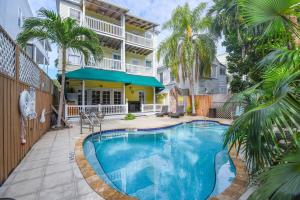 una piscina frente a una casa con palmeras en Curry House by Brightwild- 3rd Floor, King Bed, & Balcony Room 8, en Key West