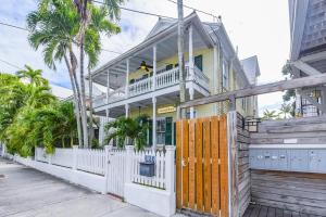 una casa amarilla con una cerca blanca y palmeras en The Curry House - Entire Complex, en Key West