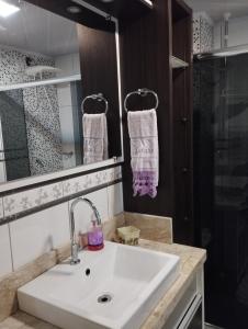 a bathroom with a white sink and a shower at Apto central completo 3 dormitórios in Caxias do Sul