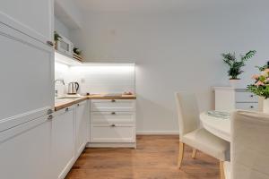 a kitchen with white cabinets and a table and chair at Seaside Apartments Baltica Tower with Gym, Sauna & Parking in Gdańsk