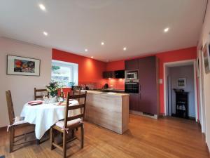 une cuisine aux murs rouges et une table avec un tissu de table blanc dans l'établissement Gîte Le Puy-en-Velay, 3 pièces, 4 personnes - FR-1-582-331, au Puy-en-Velay