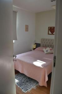 ein Schlafzimmer mit einem Bett mit einer rosa Decke in der Unterkunft Apartamento Marilândia Juiz de Fora in Juiz de Fora