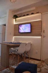a room with a table and two chairs and a tv on a wall at Apartamento Marilândia Juiz de Fora in Juiz de Fora