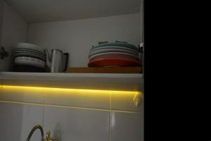 a shelf with plates and bowls on top of a kitchen cabinets at Apartamento Marilândia Juiz de Fora in Juiz de Fora