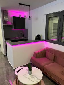 ein Wohnzimmer mit einem Sofa und eine Küche mit rosafarbener Beleuchtung in der Unterkunft MagicSpa91 in Chilly-Mazarin