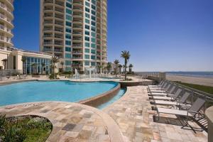 ガルベストンにあるPalisade Palms Oceanfront Condo & 5-Star Amenitiesの大きな建物、スイミングプール(椅子付)