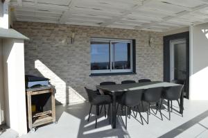 een patio met een tafel en stoelen en een bakstenen muur bij La Tourelle du Lot in Cajarc