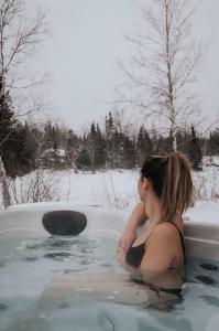 una mujer sentada en una bañera en la nieve en Chalet Le Huard, en Weedon-Centre