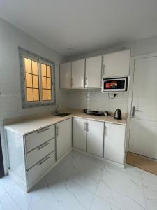 a white kitchen with white cabinets and a window at استديوهات فاخرة in Ḑubā