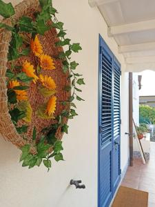 a wreath of flowers on a wall next to a blue door at Violisa Charme in Castellammare del Golfo