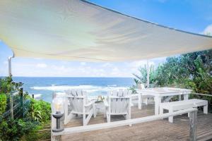 un patio con mesa, sillas y el océano en Luxury Private Beach Villa centrally located. en Westbrook