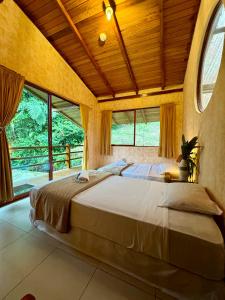 ein Schlafzimmer mit einem großen Bett in einem Zimmer mit Fenstern in der Unterkunft Wisdom Forest Lodge in Tena
