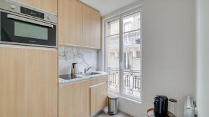 uma cozinha com um lavatório, um micro-ondas e uma janela em 162 Suite Benjamin - Superb apartment in Paris em Paris