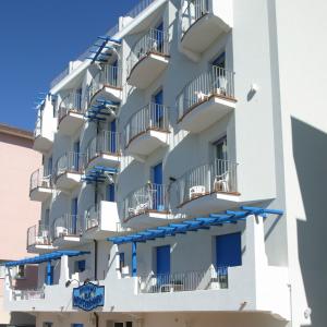 um edifício branco com varandas azuis e guarda-sóis azuis em Residence Mediterraneo em Rimini