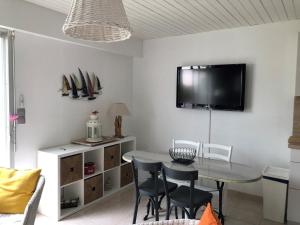 ein Esszimmer mit einem Tisch und einem TV an der Wand in der Unterkunft Gîte Noirmoutier-en-l'Île, 2 pièces, 2 personnes - FR-1-426-515 in Noirmoutier-en-l'lle