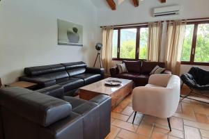 uma sala de estar com um sofá de couro e uma mesa em La Bergerie La Belle Epoque, piscine et plage em Saint-Florent