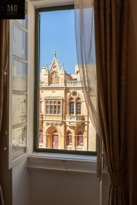 a window with a view of a large building at Palazzo EL Cattedrale in historic MDINA by 360 Estates in Mdina