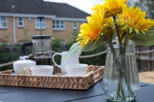 un jarrón con flores amarillas y tazas en una mesa en Perfect for Contractors with on site parking en Brettell Lane