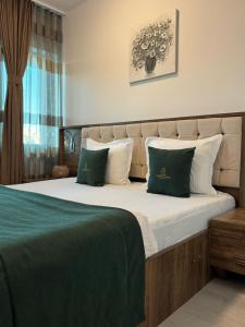 Hotel Uniluxury في بريشتيني: غرفة نوم بسرير كبير ومخدات خضراء وبيضاء