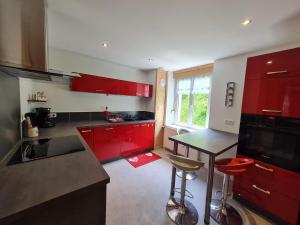 une cuisine avec des placards rouges et un comptoir noir dans l'établissement Gîte La Bresse, 3 pièces, 6 personnes - FR-1-589-410, à La Bresse
