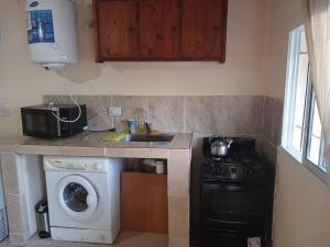 a kitchen with a sink and a washing machine at Cabaña Villa del Dique in Villa del Dique