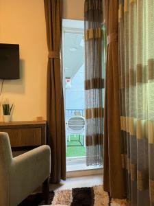Zimmer mit einem Fenster mit Vorhängen und einem Stuhl in der Unterkunft Hotel Uniluxury in Pristina