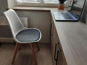 a white chair sitting next to a desk with a laptop at Gîte Vittel, 2 pièces, 2 personnes - FR-1-589-412 in Vittel