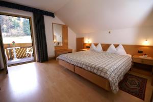 Cette chambre d'hôtel comprend un lit et un balcon. dans l'établissement Hotel Gran Pre, à San Vigilio Di Marebbe