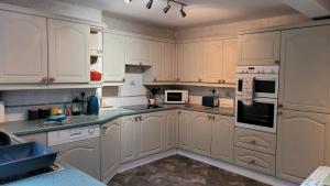 uma cozinha com armários brancos e electrodomésticos brancos em Coatham Cottage em Barton