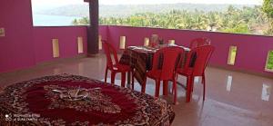 a dining room with red chairs and a table and a window at Saguntara Beach Homestay in Vengurla